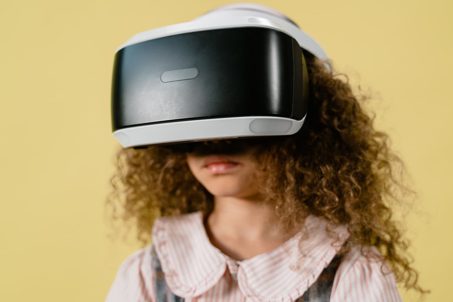 A young girl wearing a virtual reality headset, immersed in a digital experience, with a look of excitement on her face.
